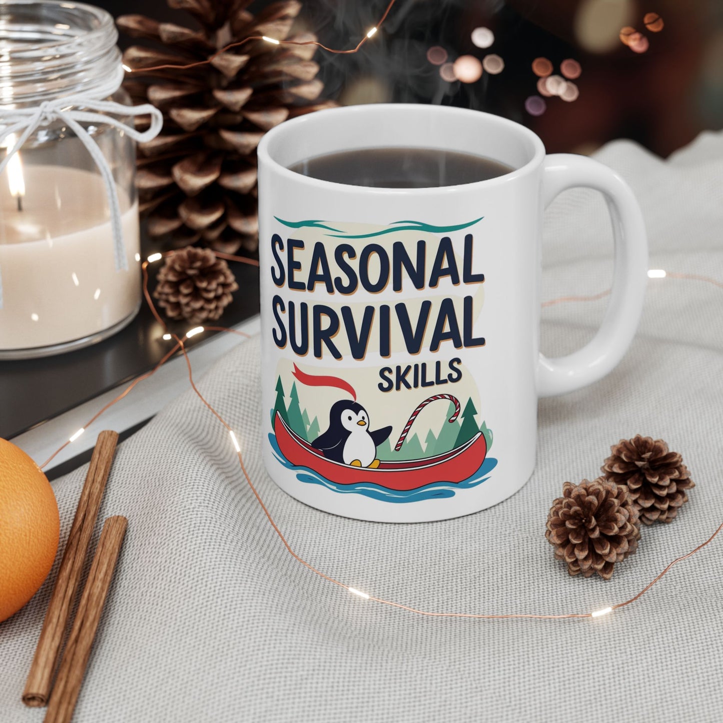 White mug with 'Seasonal Survival Skills' design featuring a penguin, surrounded by decorative items on a table.