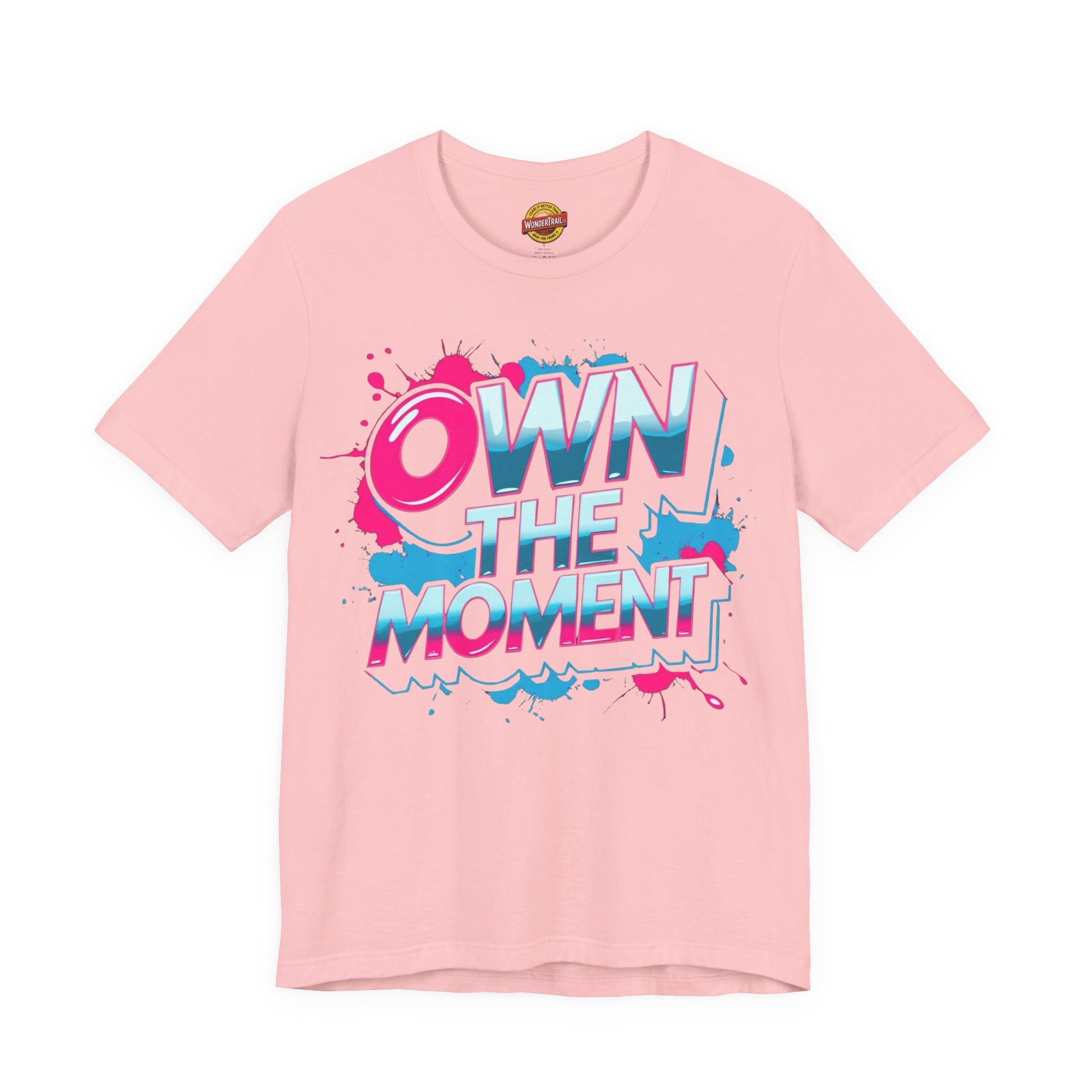 Pink t-shirt with 'OWN THE MOMENT' text and colorful design on a white background