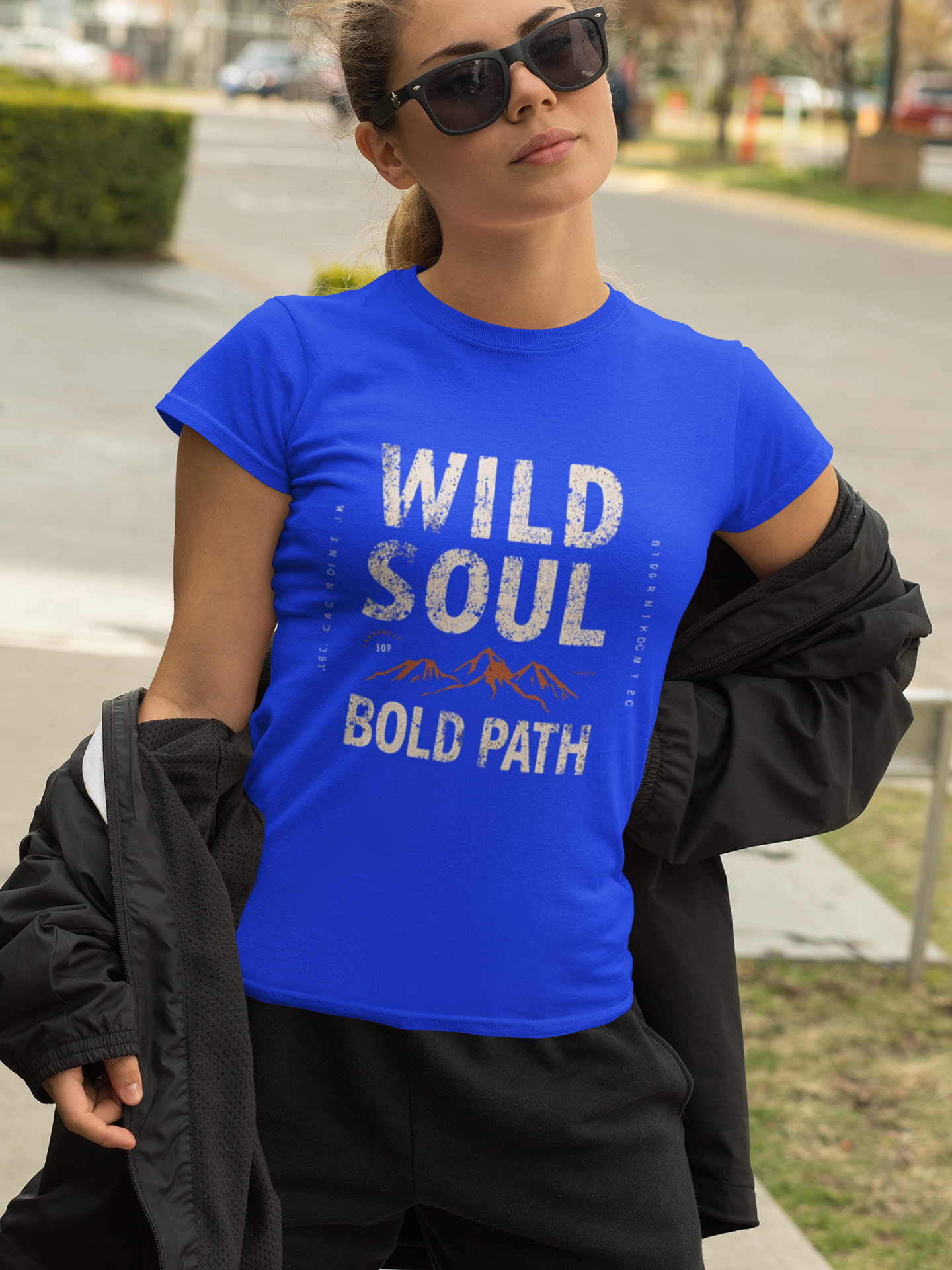 Person wearing a blue t-shirt with 'Wild Soul Bold Path' text outdoors.