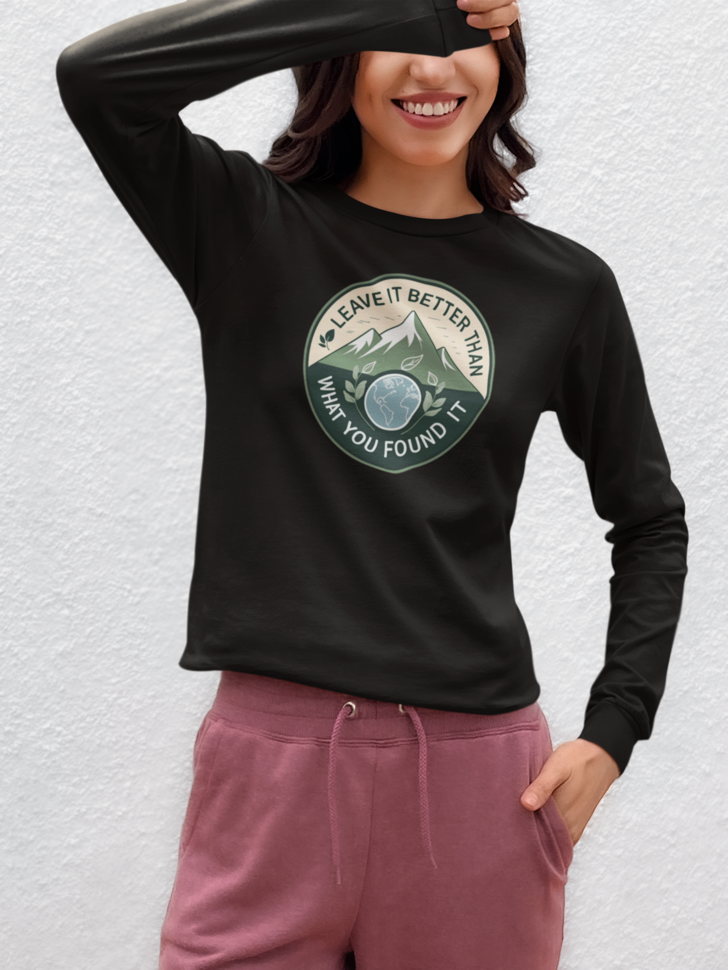 Person wearing a black long-sleeve shirt with a graphic design and pink pants on a light gray background