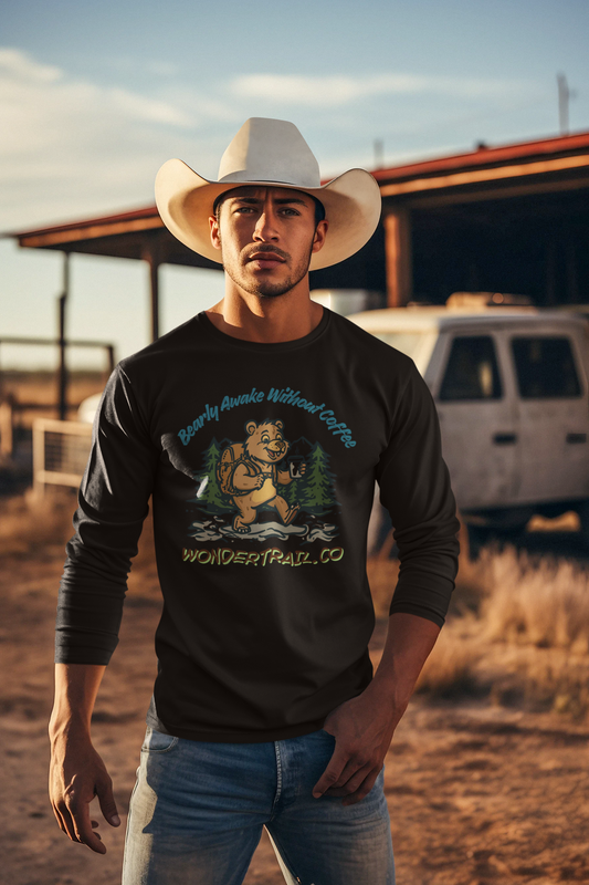 Man wearing a cowboy hat and black long-sleeve shirt with a bear graphic and text in an outdoor setting.