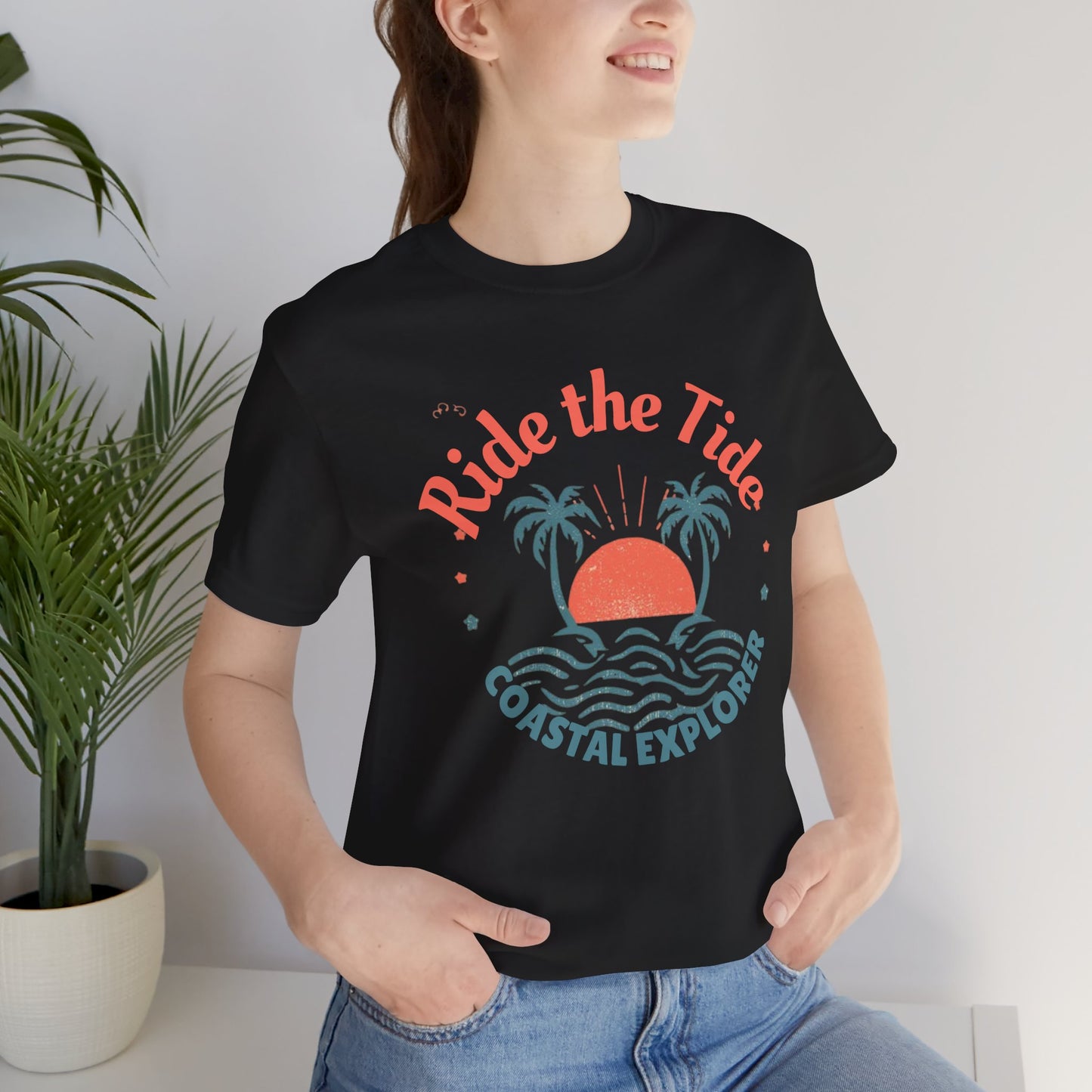 Black cotton unisex tee featuring tropical sunset and palm tree design with Ride the Tide Coastal Explorer text — stylish travel apparel for adventurers.