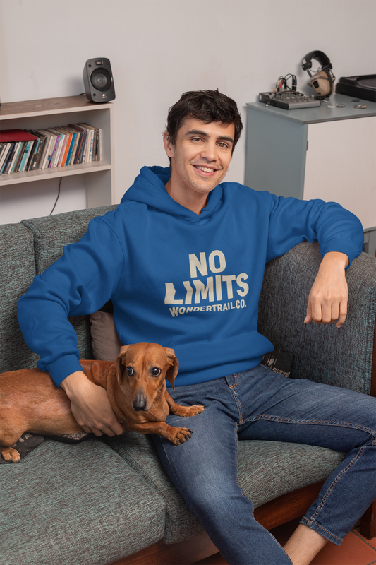 Blue hoodie with bold No Limits WonderTrail.Co slogan, casual adventure sweatshirt styled in cozy living room with dog — outdoor lifestyle apparel for explorers and nature lovers.